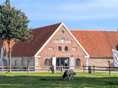 a horse grazing in front of a large brick building at 6 person holiday home in Gram in Gram