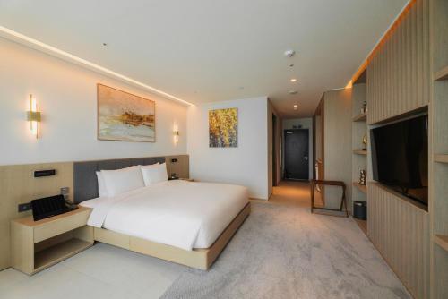 a bedroom with a white bed and a flat screen tv at WAVEM HOTEL west in Siheung