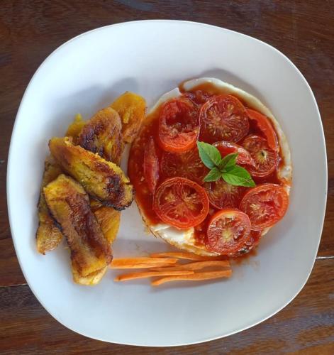 a white plate with a sandwich and tomatoes and fries at Finca Montaña Sagrada in Mérida