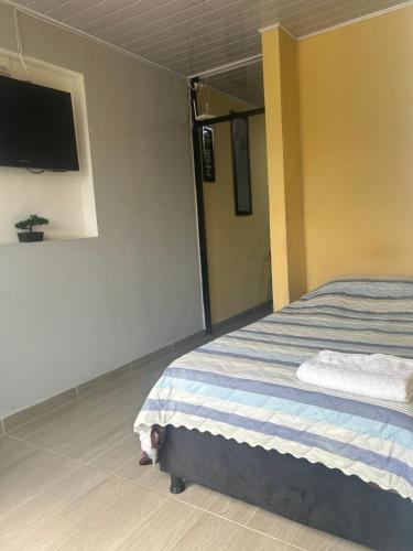 a bedroom with a bed and a flat screen tv at Acogedor y económico in Bogotá