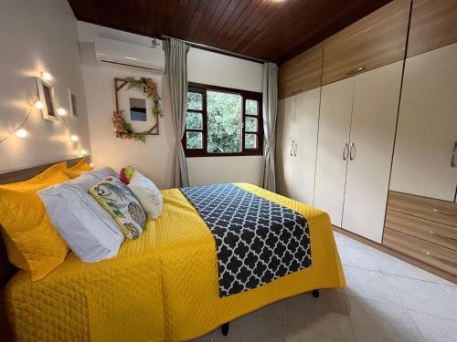 Pousada com café da manhã, piscina, natureza, sossego no Norte da Ilha, Ingleses في فلوريانوبوليس: غرفة نوم بسرير اصفر ونافذة