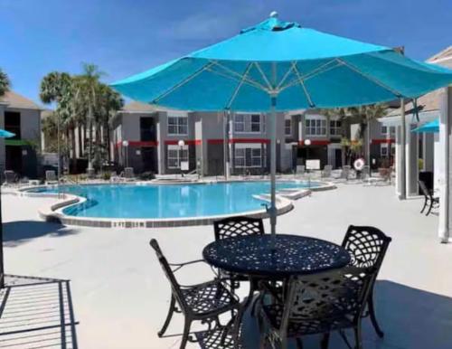 a table and chairs with an umbrella next to a pool at Condo Disney Universal Epic Free Parking in Orlando