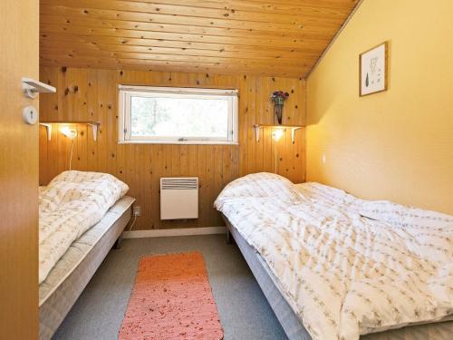two beds in a room with wooden walls and a window at Tranquil Haven near Beach - By Traum Ferienwohnungen in Rødby