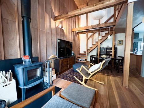 a living room with a stove and a couch and a tv at The Cozy Nest Matsukawa in Hakodate