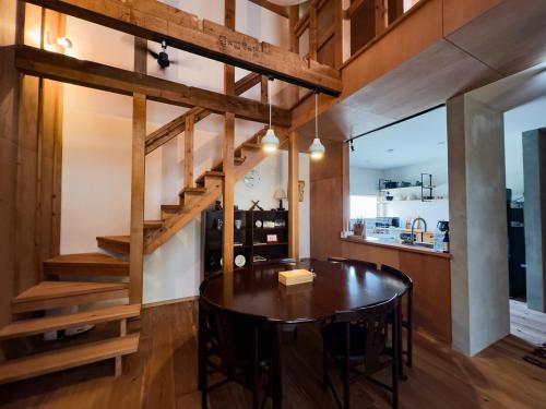 a dining room with a wooden table and stairs at The Cozy Nest Matsukawa in Hakodate