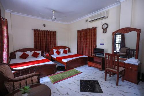 a bedroom with two beds and a desk and a chair at Sylvan Premium Guest House in Sylhet