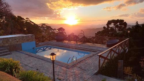 a swimming pool with a sunset in the background at Pousada Village Por do Sol by Concavus in Campos do Jordão
