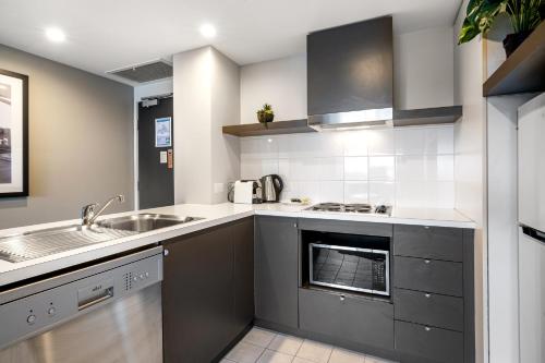 a kitchen with a sink and a stove at Spacious Apartment in Heart of Southbank in Melbourne