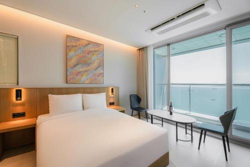 a hotel room with a bed and a desk and a window at WAVEM HOTEL west in Siheung
