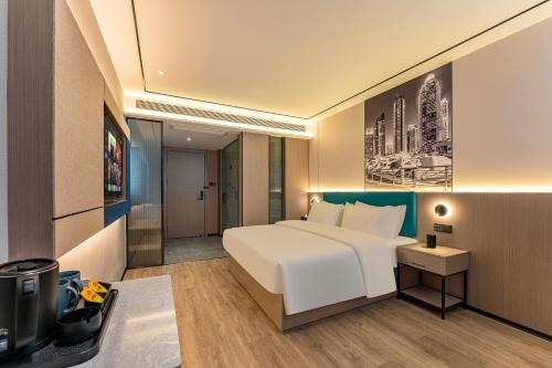 een slaapkamer met een groot wit bed en een badkamer bij Quanli Hotel, Guangzhou Tongde Metro Station Branch in Guangzhou