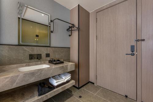 een badkamer met een wastafel en een spiegel bij Quanli Hotel, Guangzhou Tongde Metro Station Branch in Guangzhou