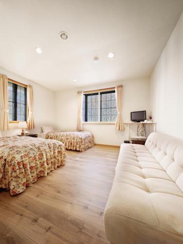 a large bedroom with two beds and a couch at カナリアンホテル in Tateshina