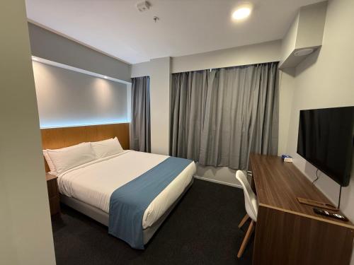 a hotel room with a bed and a flat screen tv at Goodview Hotel in Auckland