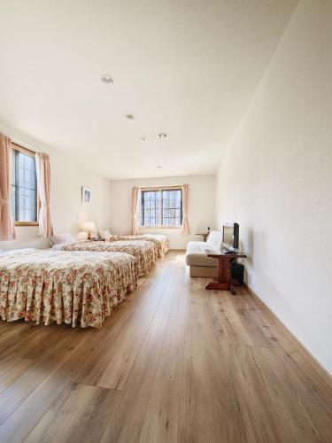 a large bedroom with two beds and a desk at カナリアンホテル in Tateshina