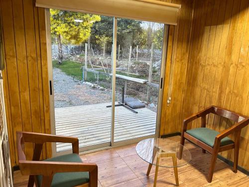 a room with a glass table and chairs and a sliding glass door at Cabañas Rivera Del Ancoa in Linares
