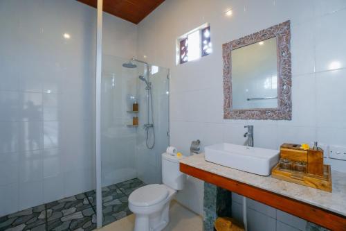 a bathroom with a toilet and a sink and a shower at Canting Bali Suite in Ubud