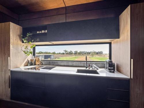 una cocina con fregadero y ventana en Samphire Chalet Peppermint - Experience Eco-Luxury, en Geographe