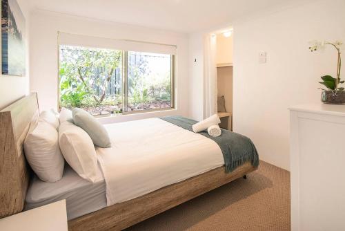 a bedroom with a large bed with pillows and a window at Peaceful Garden Hideaway - Swim, Hike and Unwind in Dunsborough