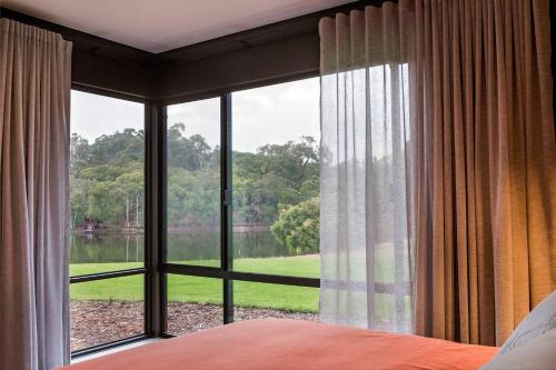 ヤリンガップにあるArtisan Koorabin - Lakeside Luxe Retreat next to Spaのベッドルーム1室(湖の景色を望む大きな窓付)