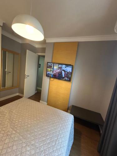 a bedroom with a bed and a flat screen tv on the wall at Hotel Aeroporto Congonhas com cozinha e sacada 1108 S in Sao Paulo