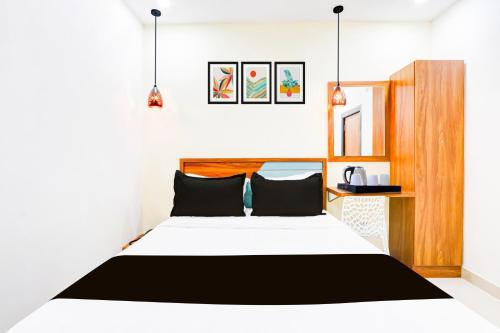 a bedroom with a white bed with black pillows at Super Townhouse Rajahmundry in Rājahmundry