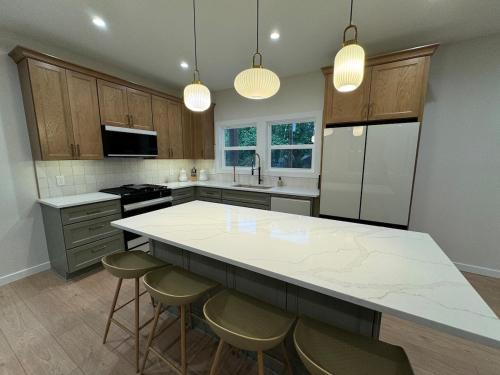 a kitchen with a large white counter and stools at European inspired cottage in Spring Lake