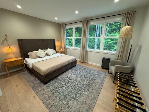 a bedroom with a bed and a chair and windows at European inspired cottage in Spring Lake