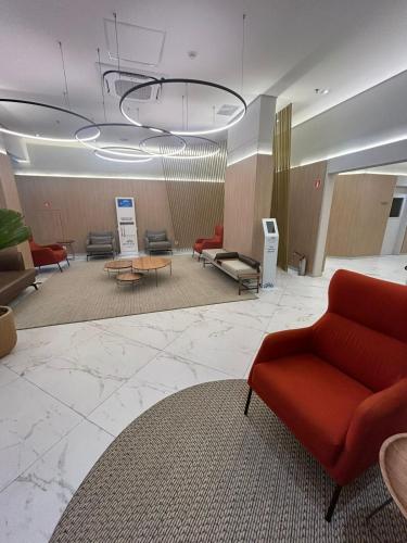 a waiting room with a red couch and chairs at Hotel Aeroporto Congonhas com cozinha e sacada 1108 S in Sao Paulo