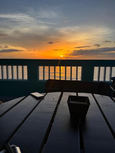 ein Tisch auf einem Schiff mit dem Sonnenuntergang im Hintergrund in der Unterkunft 1st Floor Beachfront Sleeps 6 Walkable Snorkeling 