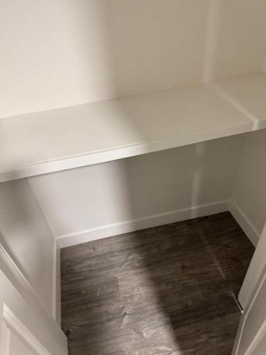 a white shelf in a room with a wooden floor at Haven Lodge, 2BR Brand New Basement Suite in Calgary