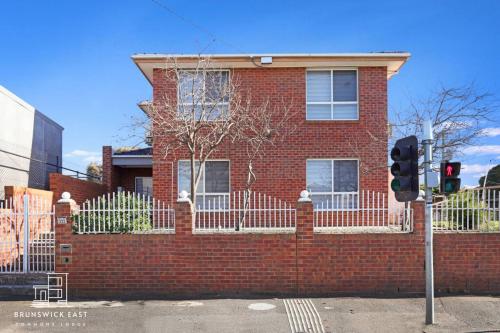 a red brick house with a fence and a traffic light at 209 Stylish Queen BR with Fast WiFi - Brunswick East in Melbourne