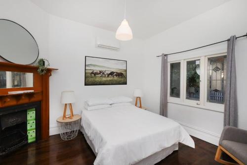 une chambre blanche avec un lit et une cheminée dans l'établissement Modern 3BR Home - 20 Mins to Melbourne CBD, à Maribyrnong