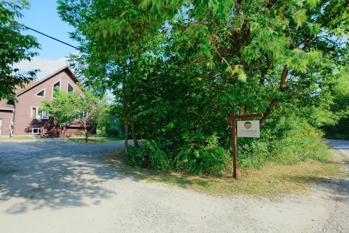 a tree with a sign in front of a house at LAuberge des Collines Escape for Two in Wakefield
