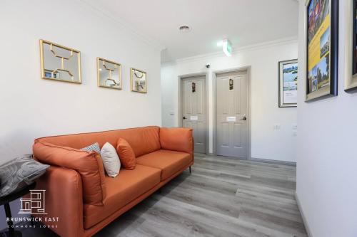 a living room with an orange couch in a room at 208 Queen BR with Fast WiFi - Brunswick East in Melbourne