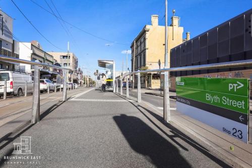 a street with a bus stop with a sign on it at 208 Queen BR with Fast WiFi - Brunswick East in Melbourne