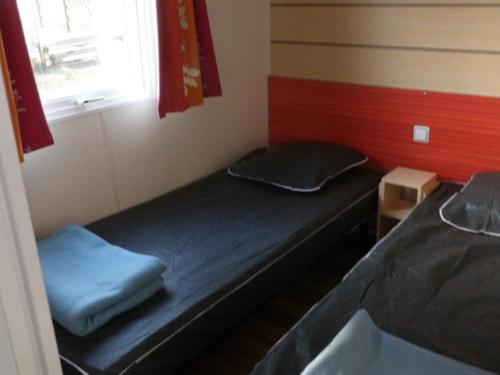 two beds in a small room with a window at Mobil Home Confortable avec Terrasse - API-1-52-390 in Saint-Sornin