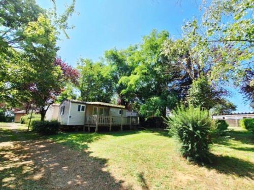 a house in the middle of a yard with trees at Chalet cosy - Vue sur l'étang avec terrasse - API-1-52-288 in Naucelle