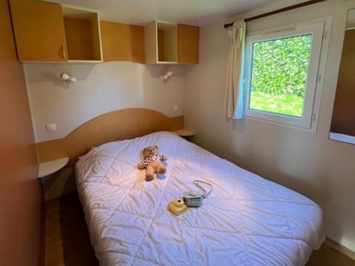 a teddy bear sitting on a bed in a bedroom at Mobil home 5 pers avec terrasse à Prailles - API-1-52-702 in Prailles