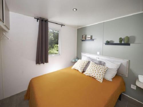 a bedroom with a yellow bed with a window at Mobil-home avec Terrasse pour 6 Personnes en Ardèche - API-1-52-360 in Saint-Maurice-dʼIbie