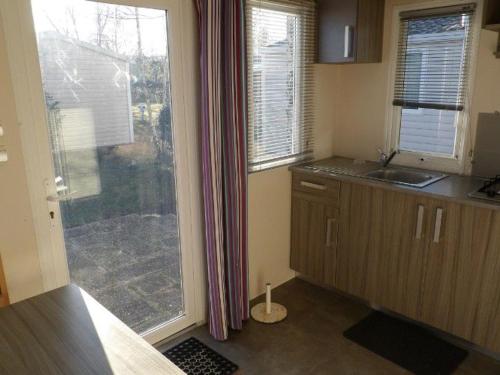 a kitchen with a large window and a sink at Mobil-home cosy avec terrasse pour 2 personnes - API-1-52-276 in Saint-Sornin