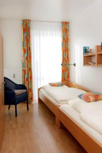 a bedroom with a bed and a chair and a window at Kaiserhof 302 in Wangerooge