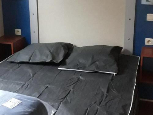 a bed covered in black sheets in a room at Mobil home 8 pers avec terrasse à Saint-Sornin - API-1-52-461 in Saint-Sornin