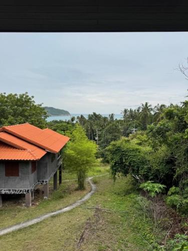 a house with an orange roof next to a dirt road at Room with a view Chaloklum in Koh Phangan