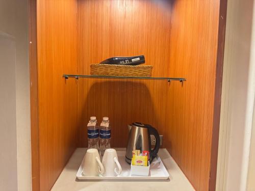 a shelf with a coffee maker and a tea kettle at Bangkok Palace Hotel in Bangkok