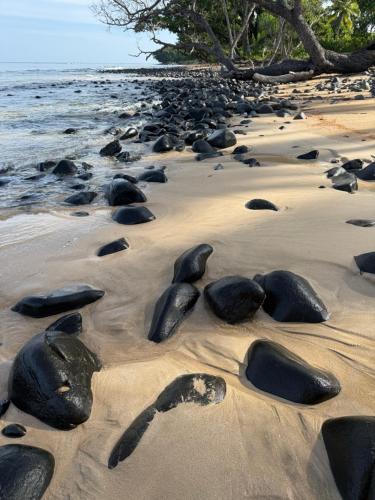 a beach with rocks in the sand and water at Kiao Beach in Anepahan