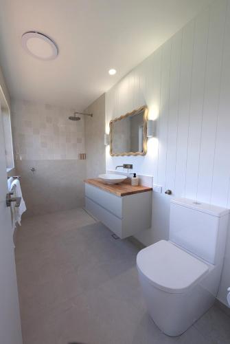 a white bathroom with a toilet and a sink at Villa Salina - 150m to One Mile Beach in Forster