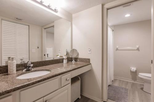 a bathroom with a sink and a toilet and a mirror at Park Shore Resort Deluxe Condo Top FloorBLDG F 339 in Naples