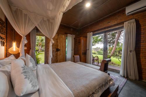 a bedroom with a large bed and a large window at Joglo Retreat in Canggu