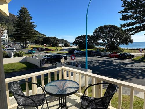 a balcony with chairs and a table and a street at Classic Kiwi Beachfront Bach in Mount Maunganui