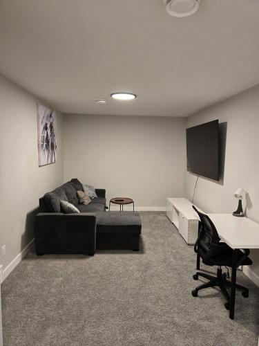 a living room with a couch and a tv and a desk at Guest Suite in Southwest Calgary in Calgary